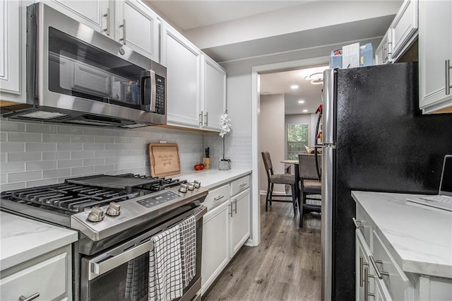 2376 Wellington Cir, Lithonia, GA 30058 - kitchen with stainless steel appliances, light wood-style floors, tasteful backsplash, and white cabinetry