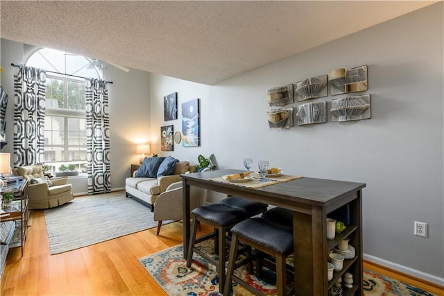 dining area featuring a textured ceiling, hardwood / wood-style flooring, and a healthy amount of sunlight