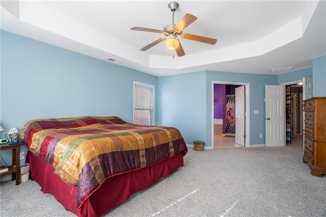 bedroom with baseboards, visible vents, a raised ceiling, and light colored carpet