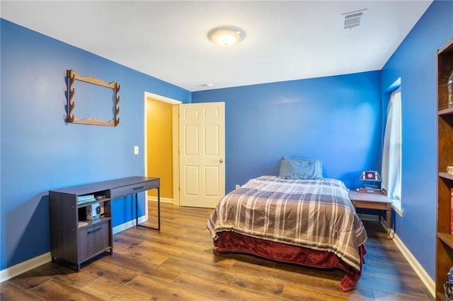 bedroom with baseboards, visible vents, and dark wood finished floors