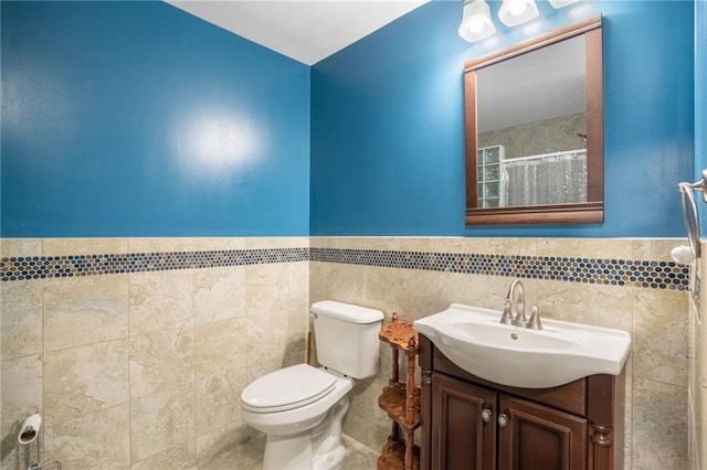 full bathroom with tile patterned floors, vanity, toilet, and tile walls