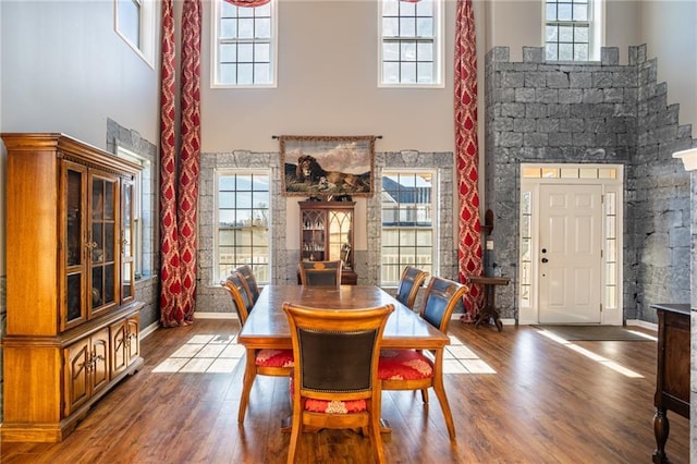 dining room featuring a towering ceiling, baseboards, and wood finished floors