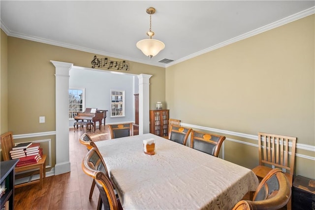 dining space featuring crown molding, dark wood finished floors, visible vents, and decorative columns