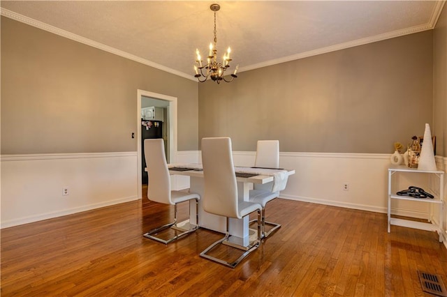 dining area featuring a chandelier, wood-type flooring, and ornamental molding