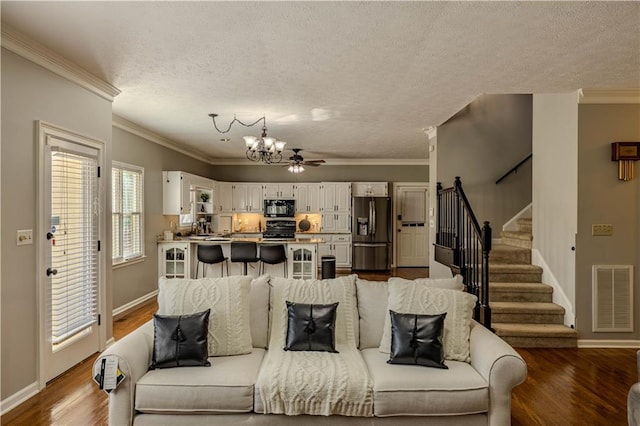 living room featuring hardwood / wood-style flooring, a notable chandelier, ornamental molding, and a textured ceiling