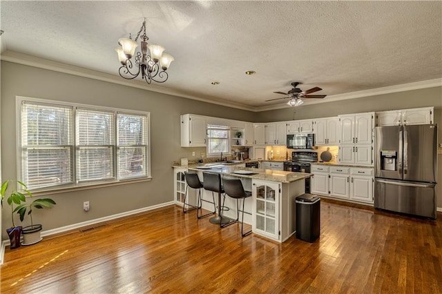 kitchen with black appliances, a kitchen breakfast bar, ceiling fan with notable chandelier, kitchen peninsula, and white cabinetry