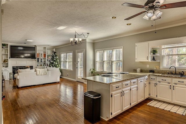 kitchen featuring white cabinets, light stone counters, ornamental molding, and sink