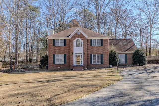 colonial-style house featuring a front lawn