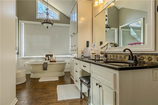 bathroom with vanity, wood-type flooring, lofted ceiling, and a tub to relax in