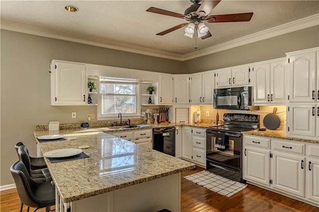 kitchen featuring light stone countertops, a breakfast bar, sink, black appliances, and white cabinetry