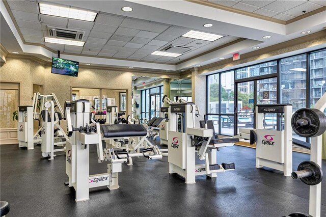 gym featuring ornamental molding, a tray ceiling, a drop ceiling, a wainscoted wall, and recessed lighting