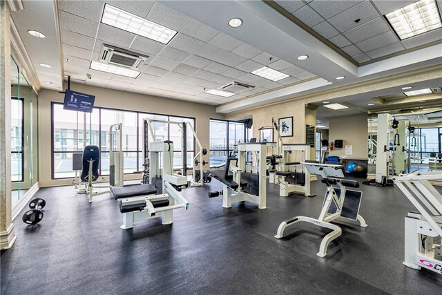 exercise room featuring a paneled ceiling and baseboards