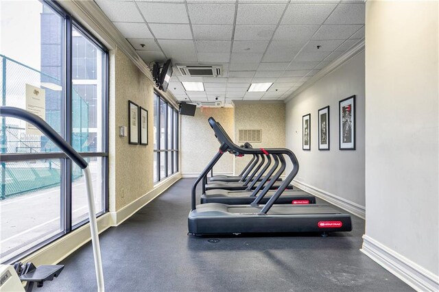 exercise room with baseboards and a drop ceiling