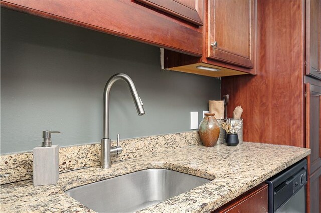 kitchen with stainless steel appliances, a sink, dark tile patterned floors, baseboards, and light stone counters