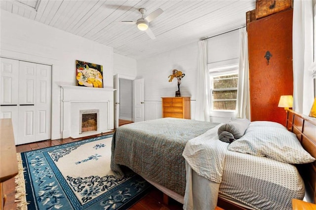 bedroom featuring a closet, a fireplace, wooden ceiling, and wood finished floors