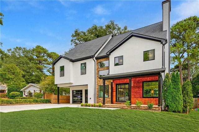 modern farmhouse style home with concrete driveway, a chimney, fence, a front lawn, and stucco siding