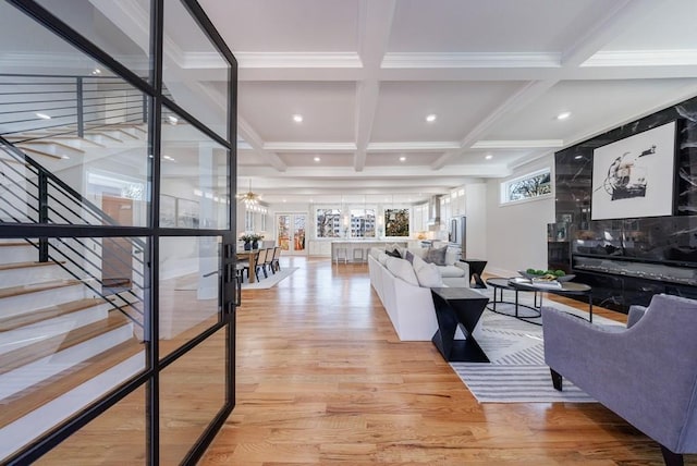 living room with beamed ceiling, ornamental molding, coffered ceiling, and light wood-type flooring