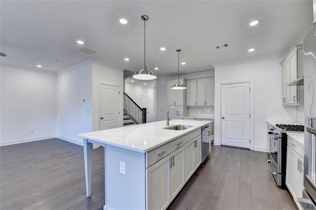 kitchen featuring sink, a kitchen island with sink, decorative light fixtures, decorative backsplash, and appliances with stainless steel finishes