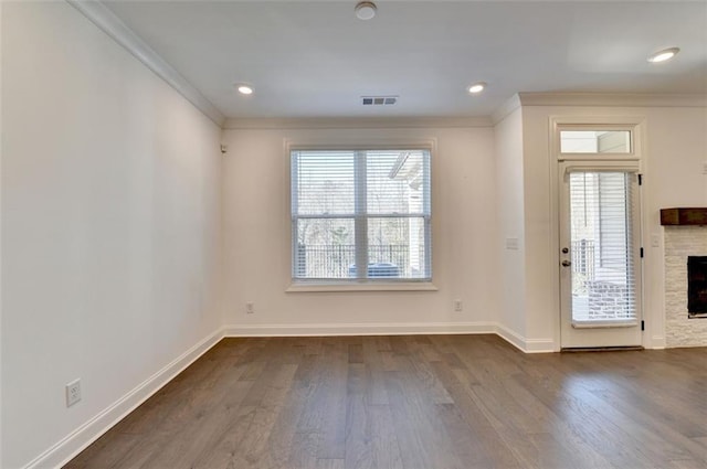 entryway featuring a stone fireplace, ornamental molding, dark wood-type flooring, and a wealth of natural light