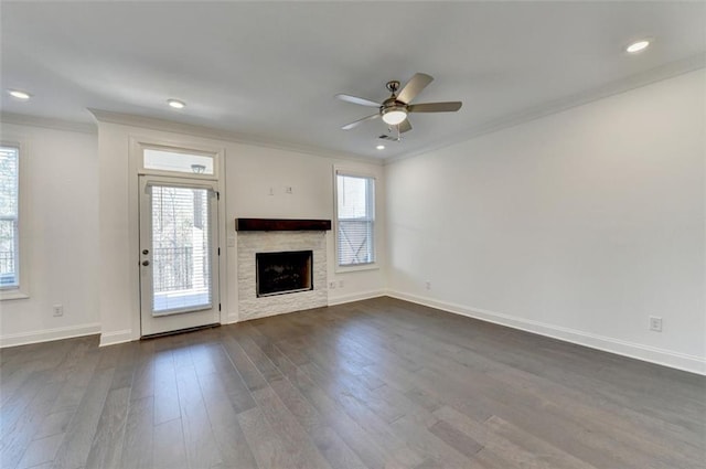 unfurnished living room with dark hardwood / wood-style floors, ceiling fan, a stone fireplace, and ornamental molding