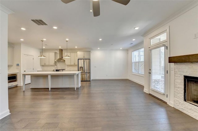 living room featuring a stone fireplace, ceiling fan, dark hardwood / wood-style flooring, and ornamental molding