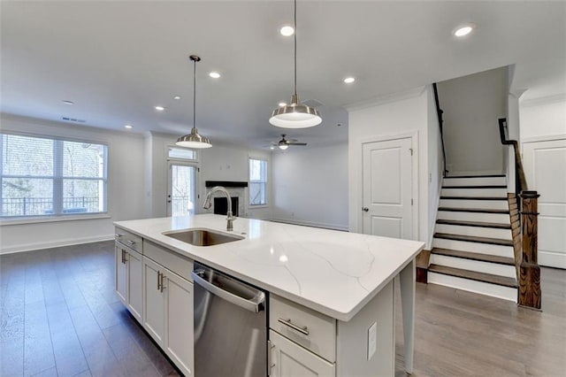 kitchen featuring dishwasher, sink, hanging light fixtures, and an island with sink