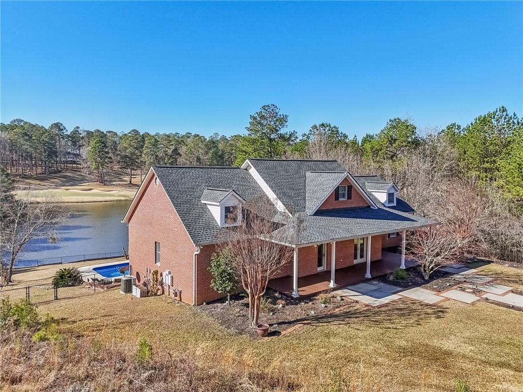 view of front of house featuring a front yard, a water view, central AC unit, and a patio area