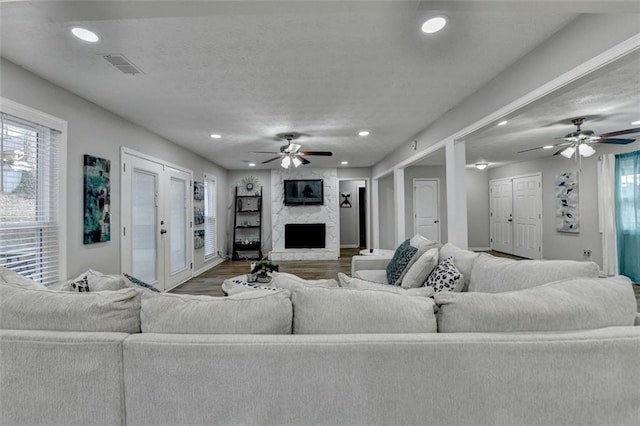 living room with wood-type flooring, a textured ceiling, ceiling fan, and a high end fireplace