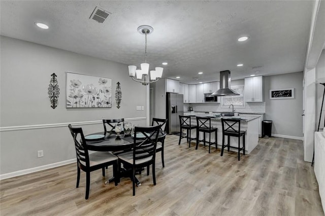 dining room featuring a chandelier, a textured ceiling, and light wood-type flooring