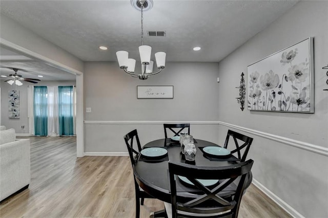 dining area featuring ceiling fan with notable chandelier and light hardwood / wood-style flooring