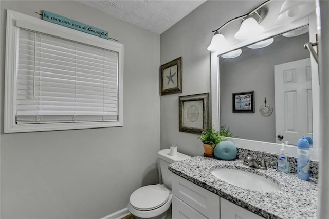 bathroom with vanity, toilet, and a textured ceiling