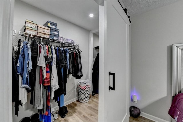 spacious closet with a barn door and hardwood / wood-style floors