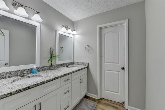 bathroom featuring hardwood / wood-style flooring, vanity, and a textured ceiling