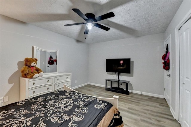 bedroom featuring ceiling fan, a closet, wood-type flooring, and a textured ceiling