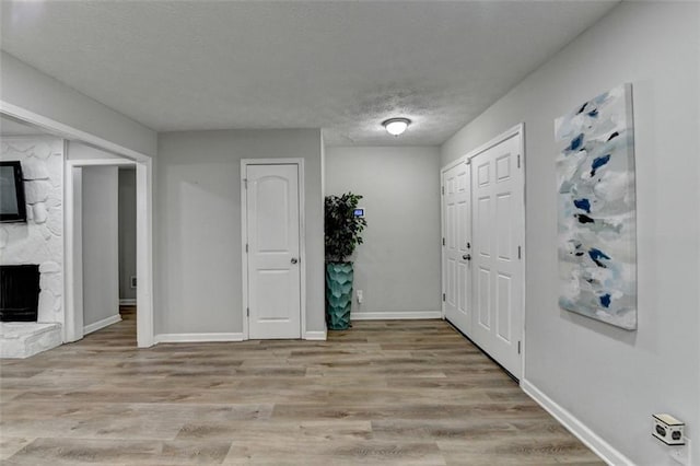 entrance foyer with a fireplace, light hardwood / wood-style floors, and a textured ceiling