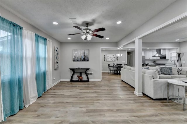 living room with ceiling fan, light hardwood / wood-style flooring, and a textured ceiling