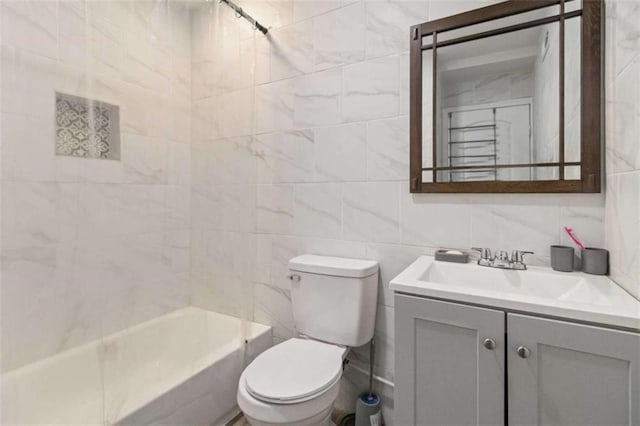 full bathroom with vanity, tiled shower / bath combo, tile walls, and toilet