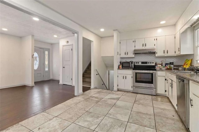 kitchen with backsplash, white cabinets, sink, light hardwood / wood-style flooring, and appliances with stainless steel finishes