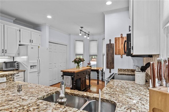 kitchen featuring ornamental molding, hardwood / wood-style floors, white cabinets, and white refrigerator with ice dispenser