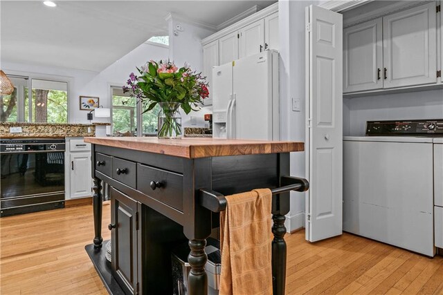 kitchen featuring dishwasher, white refrigerator with ice dispenser, light hardwood / wood-style floors, white cabinetry, and washer / dryer