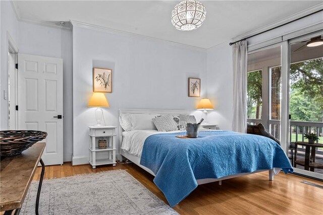 bedroom with light wood-type flooring, ornamental molding, and access to exterior