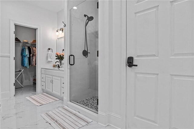 bathroom featuring a shower with shower door and vanity