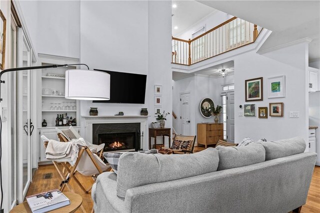 living room featuring crown molding, a high ceiling, hardwood / wood-style floors, and a fireplace