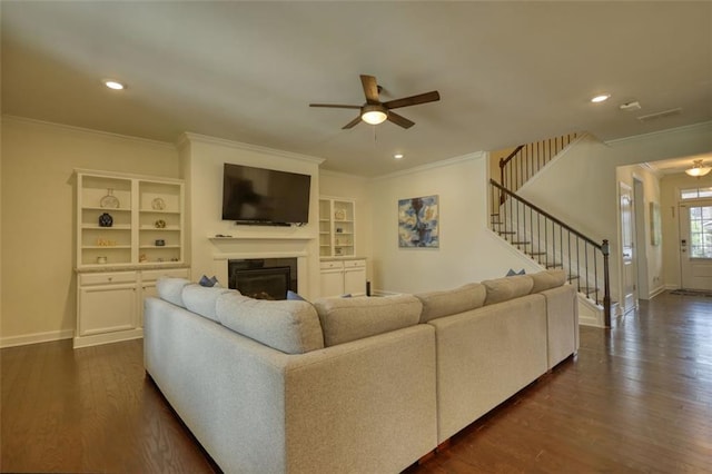 4895 Sterling Close, Buford, GA 30518 - living room featuring ceiling fan, ornamental molding, a glass covered fireplace, stairs, and dark wood-style flooring
