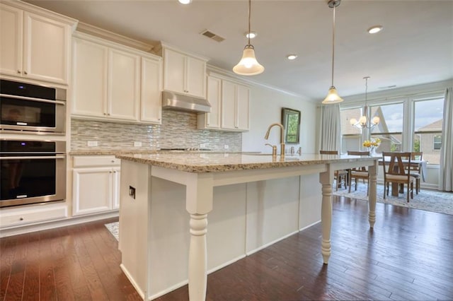 4895 Sterling Close, Buford, GA 30518 - kitchen with under cabinet range hood, dark wood finished floors, backsplash, double oven, and recessed lighting