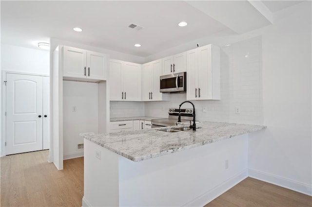 kitchen with sink, stainless steel appliances, kitchen peninsula, and white cabinets