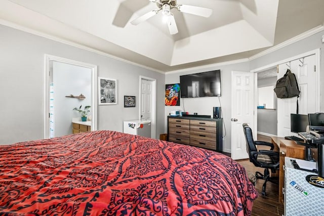 bedroom featuring a ceiling fan, ornamental molding, wood finished floors, ensuite bathroom, and a tray ceiling