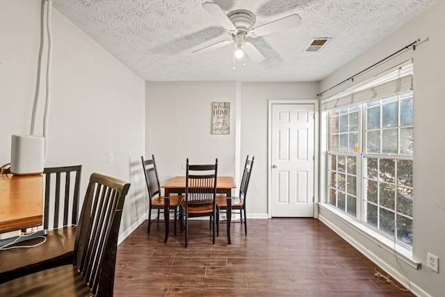 dining space with ceiling fan, a textured ceiling, dark wood-type flooring, visible vents, and baseboards