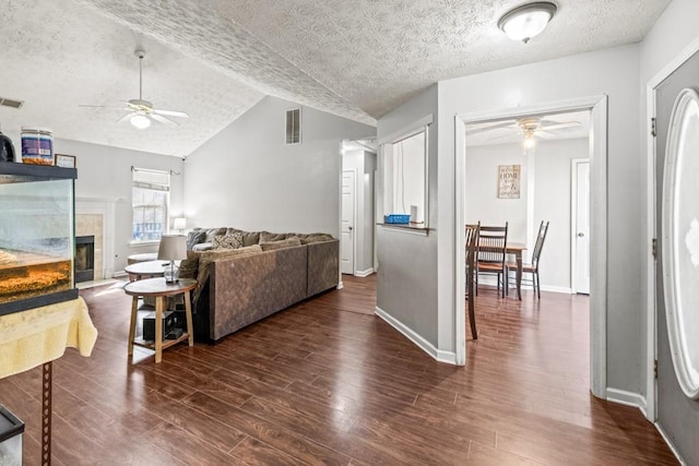 living area with visible vents, vaulted ceiling, wood finished floors, and a tile fireplace