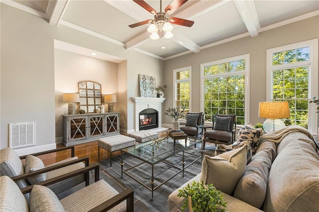 living room featuring ceiling fan, ornamental molding, a healthy amount of sunlight, and beamed ceiling